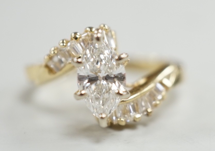 A yellow metal and singe stone marquise cut diamond set crossover dress ring, with baguette cut diamond set shoulders, size J/K, gross weight 3.2 grams.